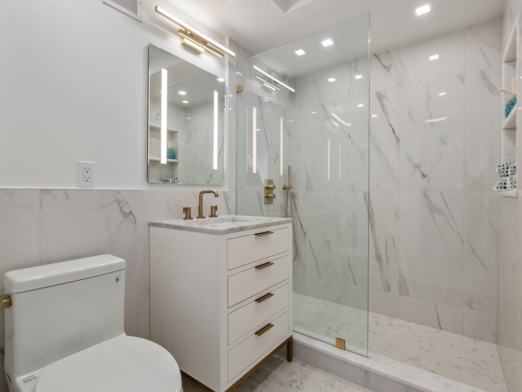 80 Park Street, Unit 24 Brookline, MA 02446 - Photo 14 of 17 a bathroom with a shower sink vanity mirror and toilet