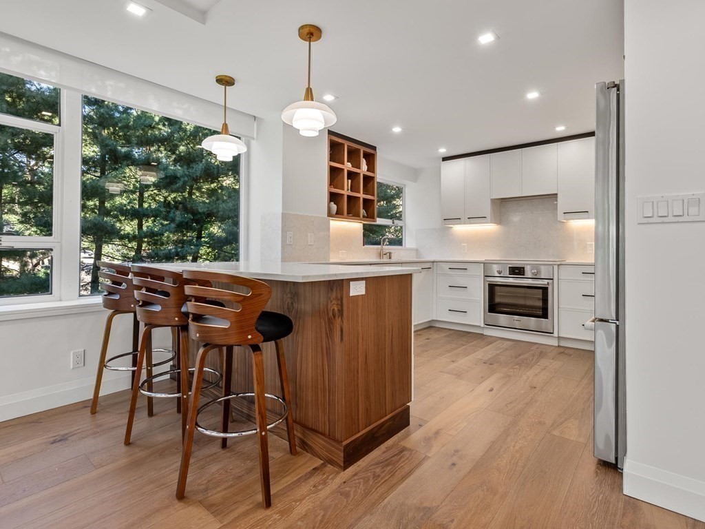 80 Park Street, Unit 24 Brookline, MA 02446 - Photo 2 of 17 a kitchen with stainless steel appliances granite countertop wooden floors and white cabinets