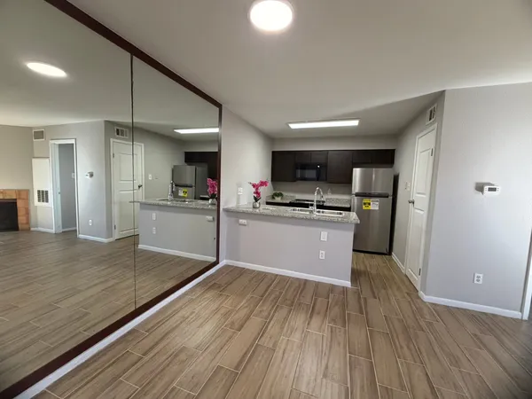 a kitchen with stainless steel appliances granite countertop a refrigerator a sink dishwasher a stove and white countertops with wooden floor