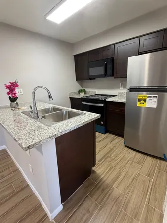 a kitchen with granite countertop a refrigerator and a stove top oven