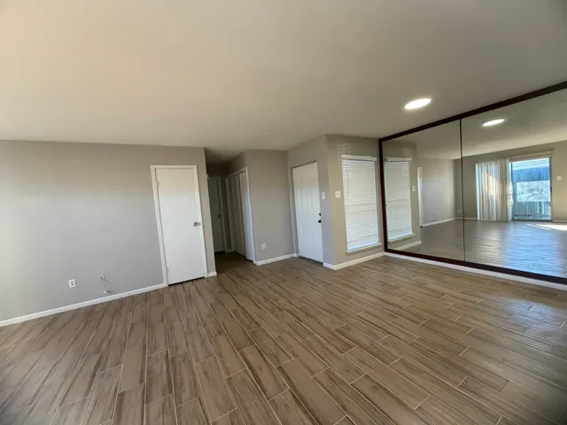 a view of an empty room with wooden floor and a window