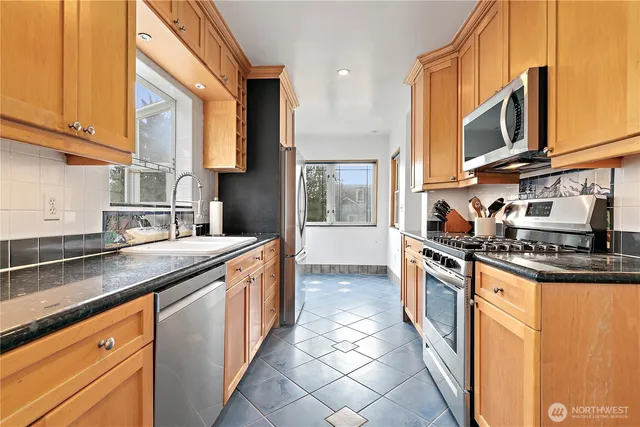 a kitchen with stainless steel appliances granite countertop a stove a sink and a microwave