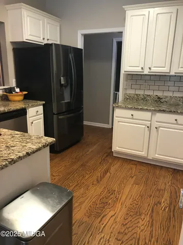 a kitchen with stainless steel appliances granite countertop a refrigerator a stove and a sink with wooden floor