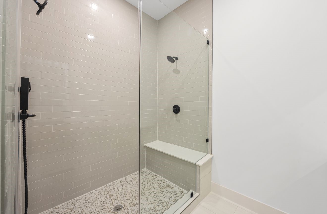 2121 Hoskins Drive, Unit C Houston, TX 77080 - Photo 28 of 34 Glass-enclosed shower with neutral subway-style tile, pebble-style shower floor, built-in bench, and matte black fixtures. The frameless glass design keeps the space feeling open and bright, while the clean tilework and modern finishes create a refined, spa-inspired shower experience.