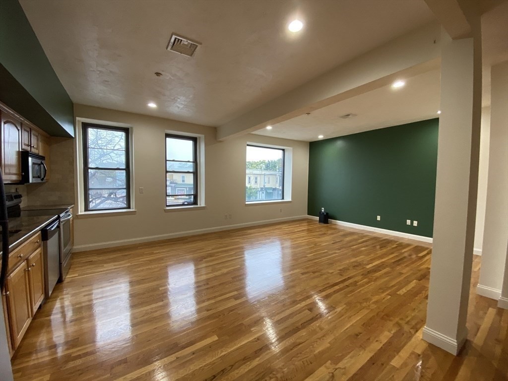 a view of an empty room with window and wooden floor