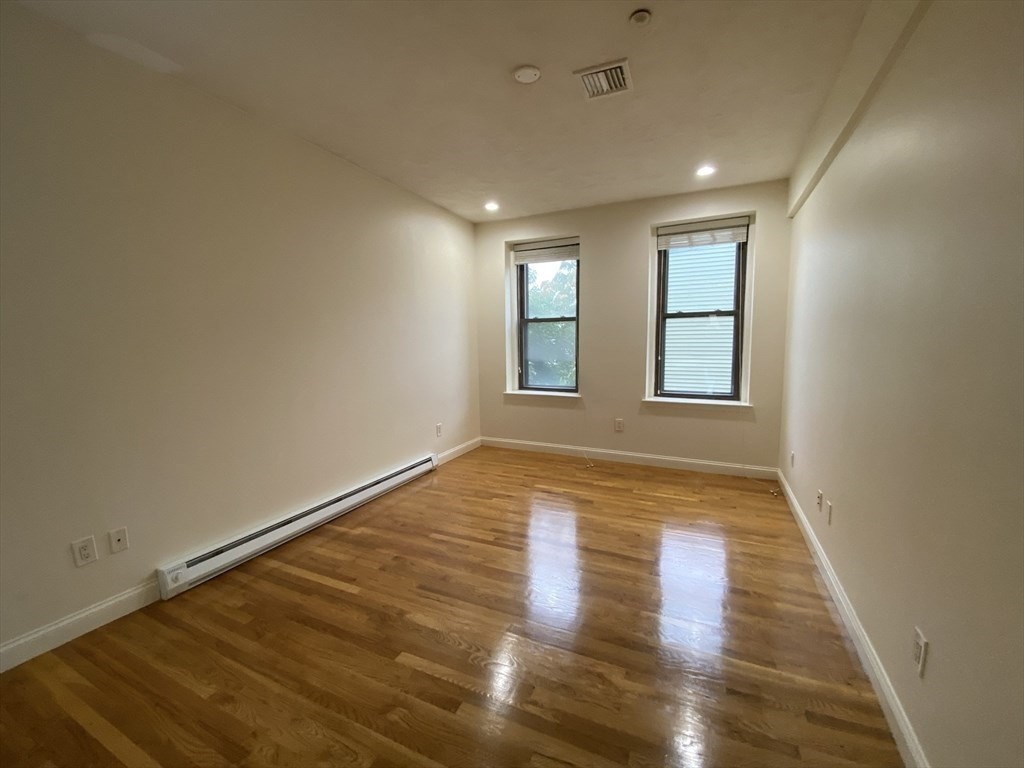 1008 Bennington Street, Unit 4A Boston, MA 02128 - Photo 4 of 9 an empty room with wooden floor and windows
