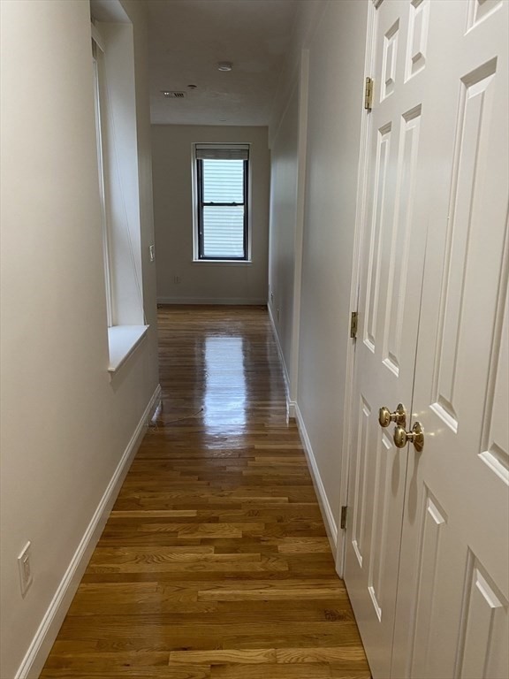 1008 Bennington Street, Unit 4A Boston, MA 02128 - Photo 5 of 9 a view of a hallway with wooden floor and staircase