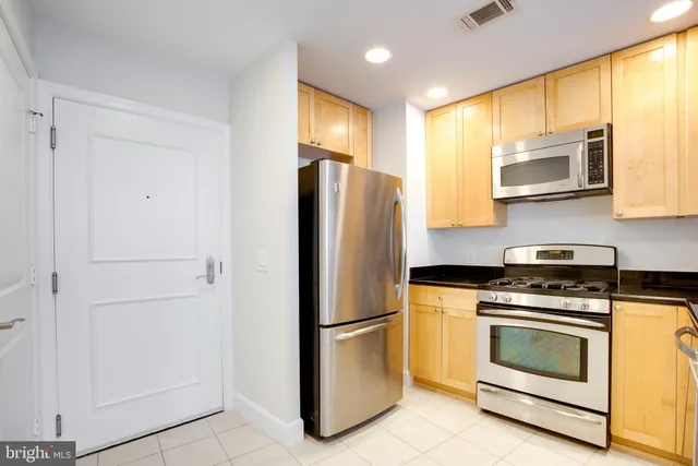 a kitchen with stainless steel appliances white cabinets and a refrigerator