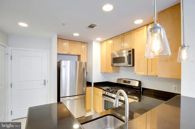 a kitchen with kitchen island a refrigerator a sink and a counter top space
