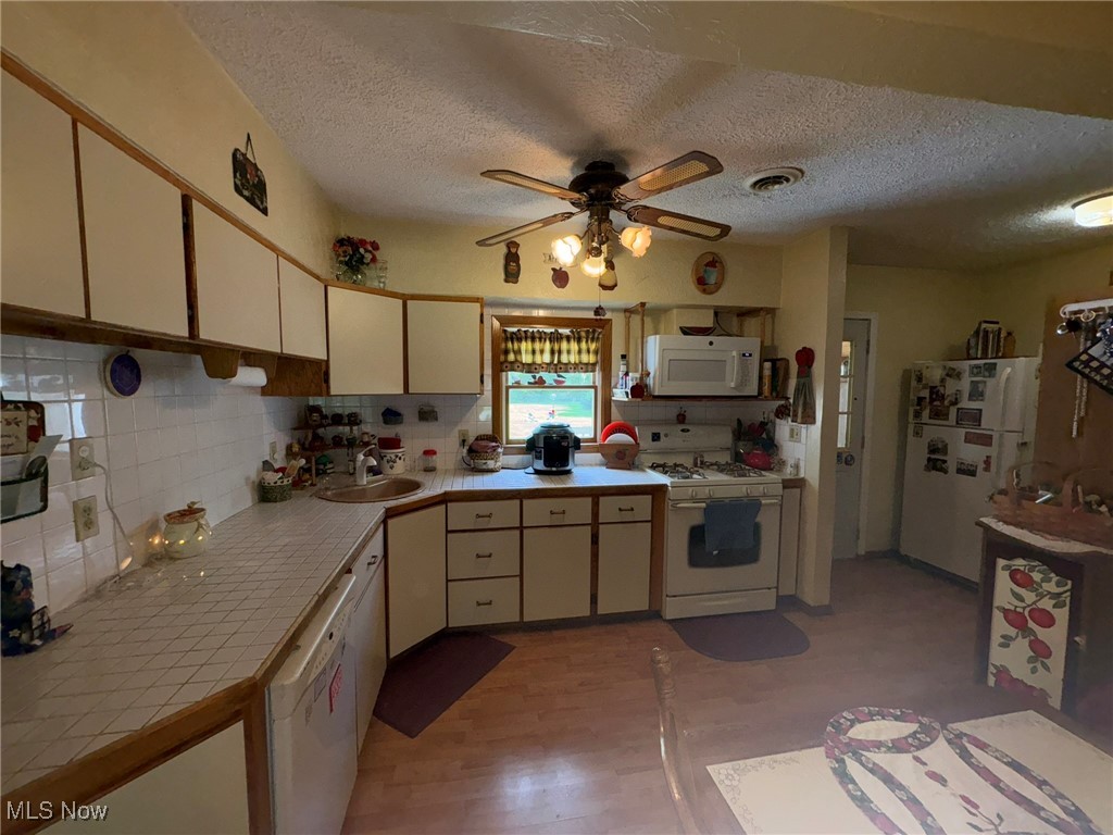 3181 Jaycox Road Avon, OH 44011 - Photo 15 of 48 Kitchen with white appliances, tile countertops, a sink, a ceiling fan, and a textured ceiling
