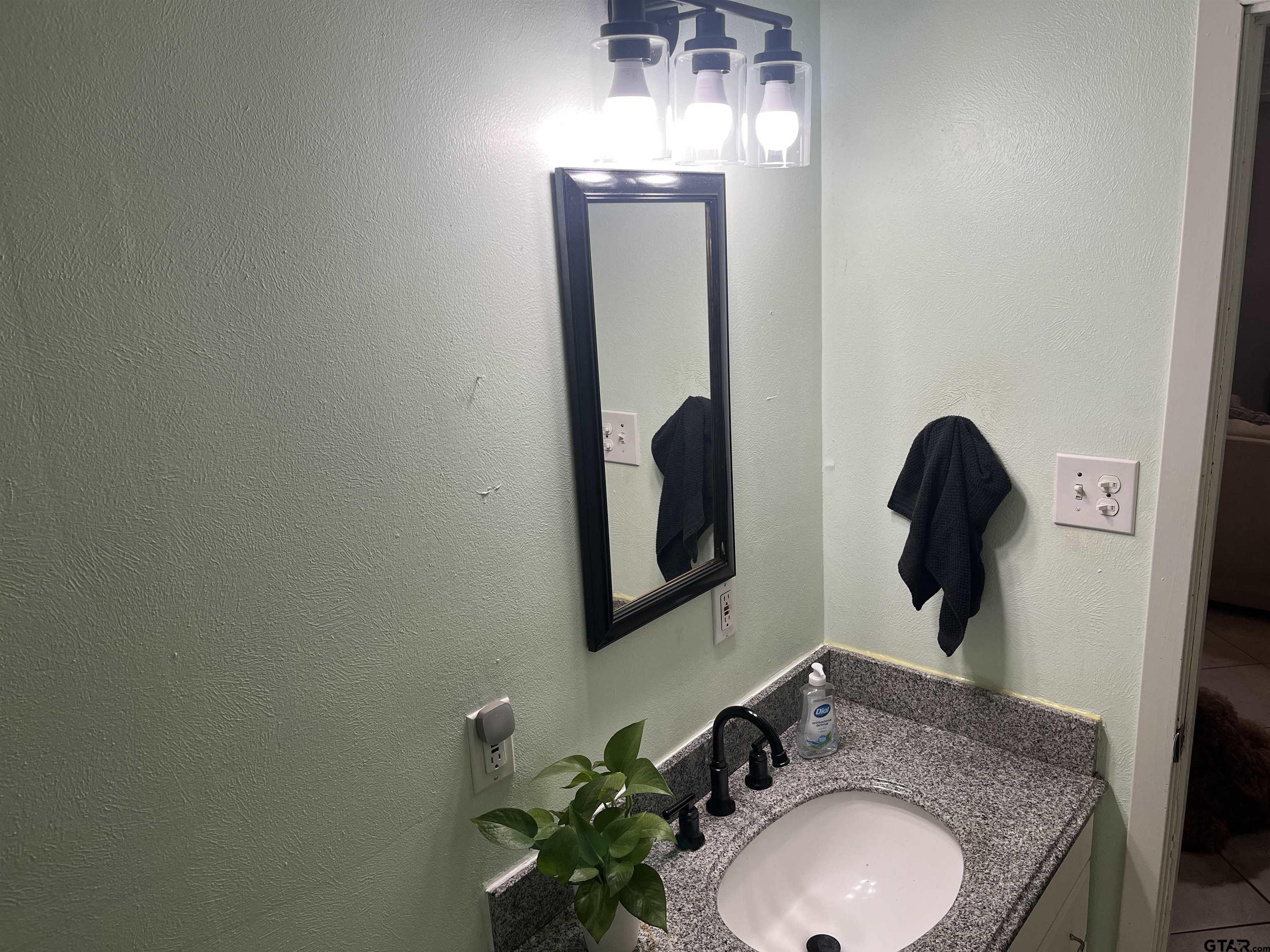 407 Fulton Street Pittsburg, TX 75686 - Photo 17 of 30 a bathroom with a granite countertop sink and a mirror
