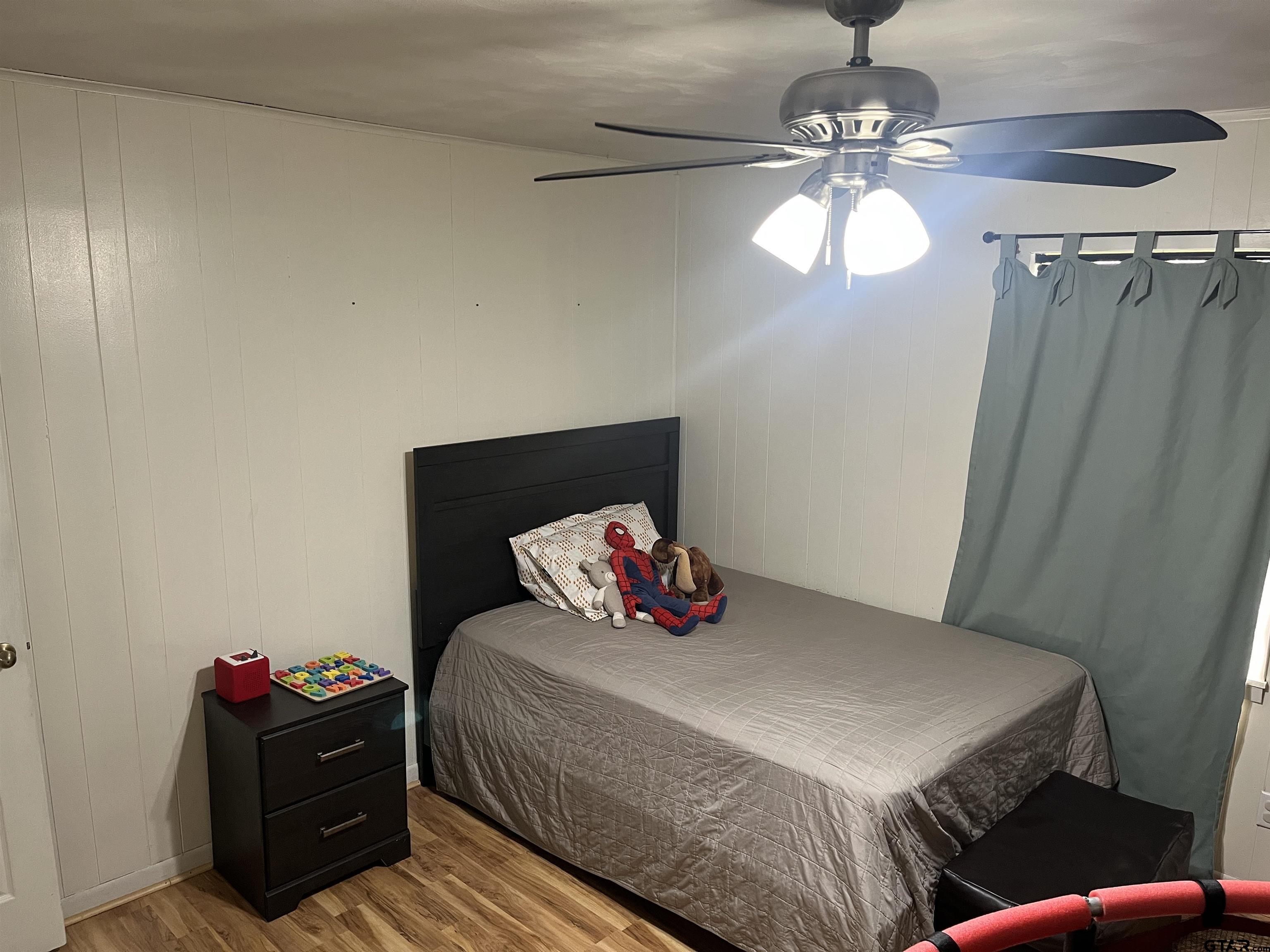 407 Fulton Street Pittsburg, TX 75686 - Photo 21 of 30 a bedroom with a bed and wooden floor
