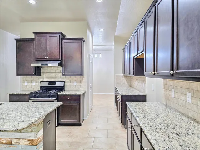a kitchen with stainless steel appliances granite countertop wooden cabinets a stove top oven and granite counter tops