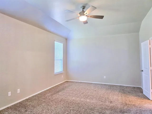 an empty room with a chandelier fan and windows