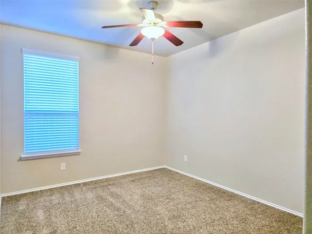 an empty room with a window and a fan