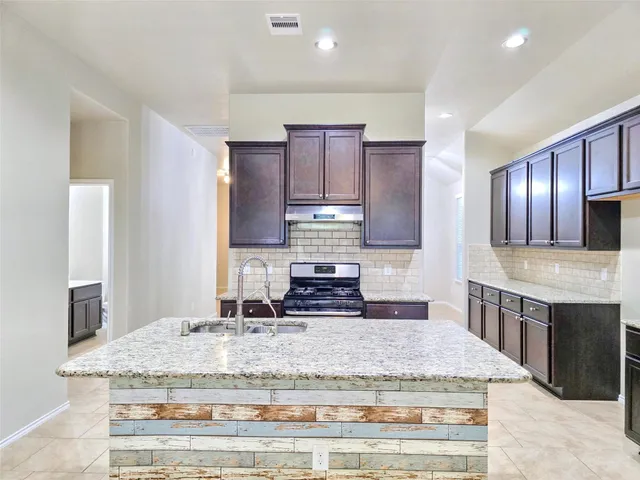 a kitchen with kitchen island granite countertop wooden cabinets and a sink