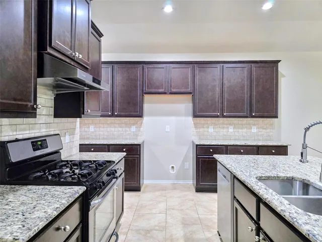 a kitchen with granite countertop a sink stove and cabinets