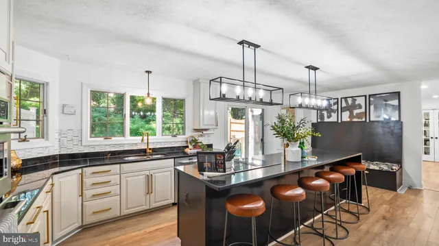 a kitchen with stainless steel appliances granite countertop a sink a stove and a wooden floors