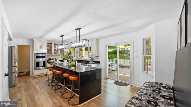 a living room with stainless steel appliances granite countertop furniture and a wooden floor