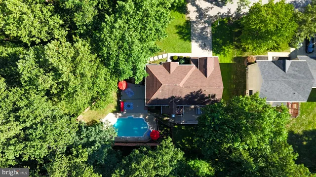 an aerial view of residential house with outdoor space and trees all around