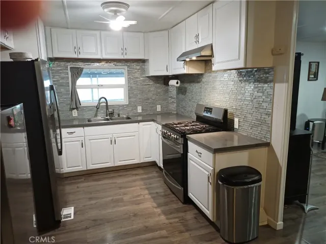 a kitchen with stainless steel appliances granite countertop a stove a sink dishwasher a refrigerator and a oven with wooden floor