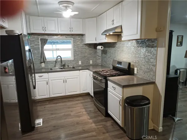 a kitchen with stainless steel appliances granite countertop a stove a sink dishwasher a refrigerator and a oven with wooden floor