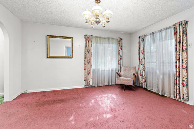 Arched doorway leading into the room, textured ceiling, and a multi-arm chandelier