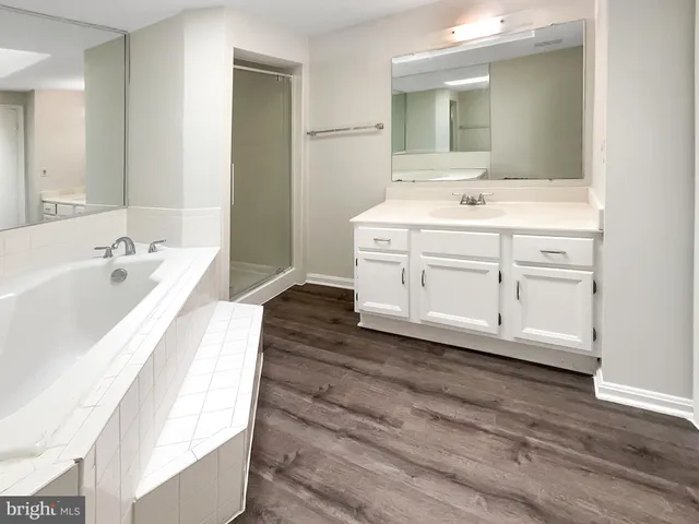 a spacious bathroom with a tub sink and mirror