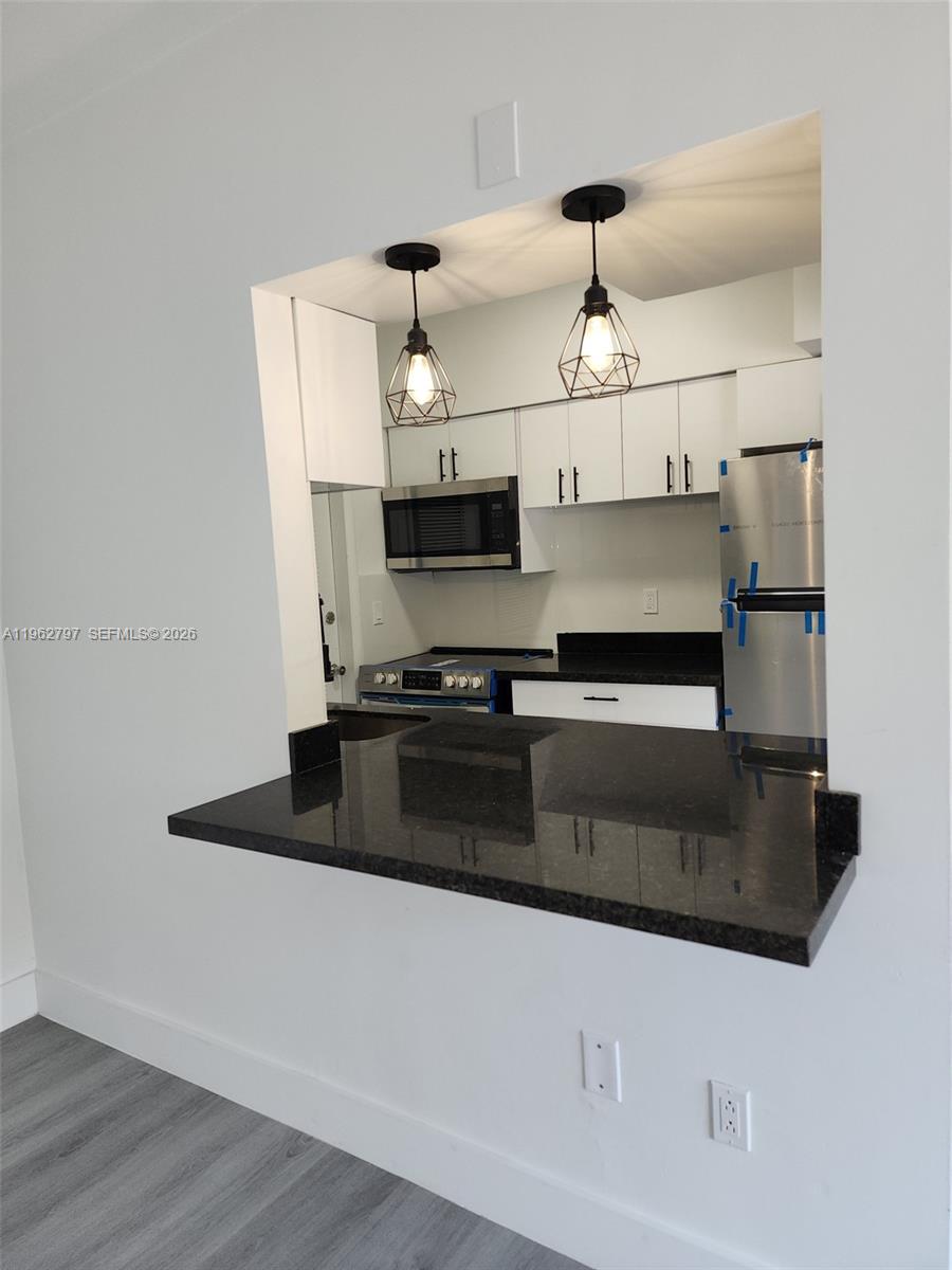 2101 Normandy Drive, Unit 204 Miami Beach, FL 33141 - Photo 31 of 43 a kitchen with kitchen island granite countertop a sink and a stove