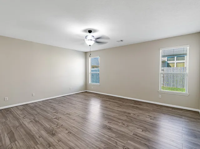 a view of a room with wooden floor and a ceiling fan