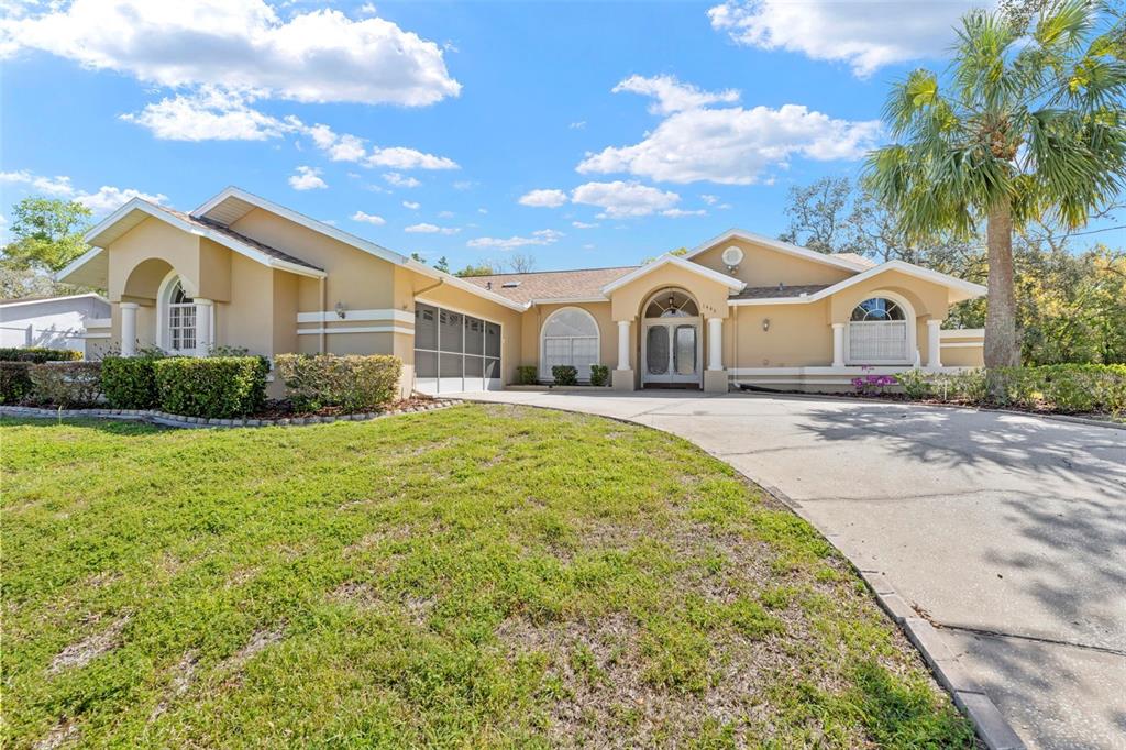 1446 Cornell Avenue Spring Hill, FL 34609 - Photo 1 of 39 a front view of a house with a garden