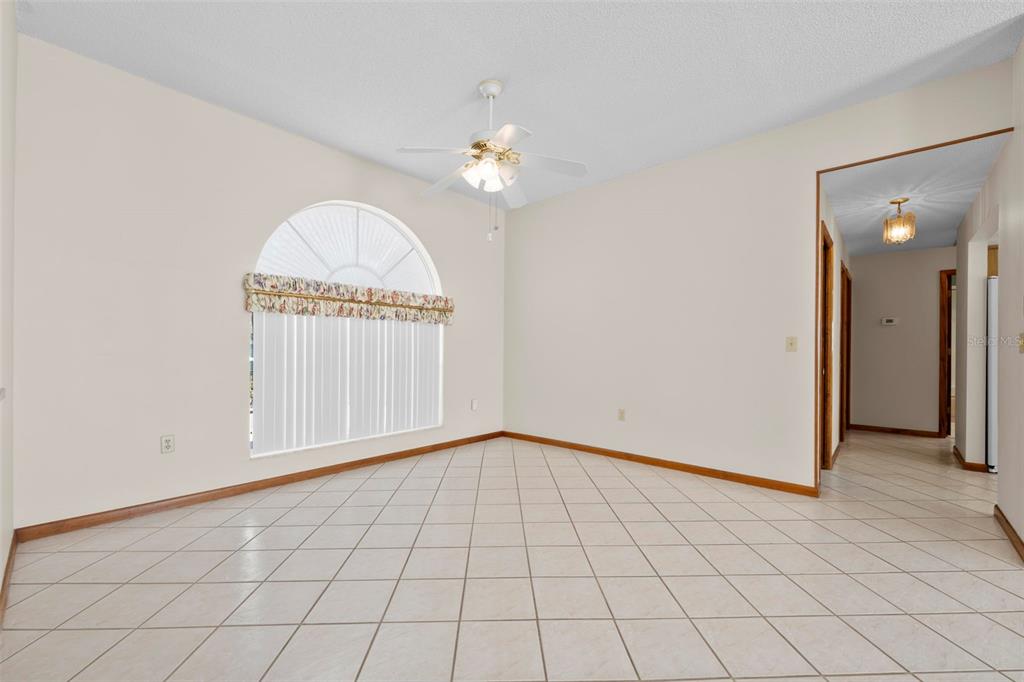 1446 Cornell Avenue Spring Hill, FL 34609 - Photo 5 of 39 an empty room with chandelier fan and windows
