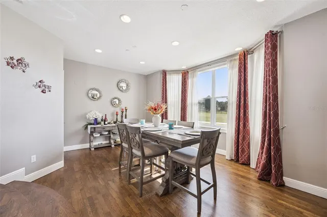 a kitchen with stainless steel appliances a dining table chairs and wooden floor