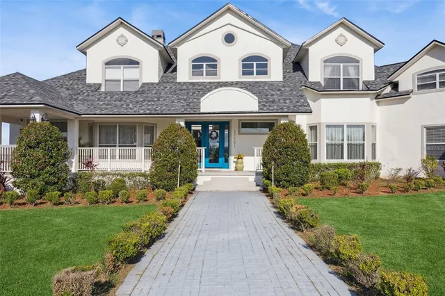 a view of a white house next to a yard with big trees