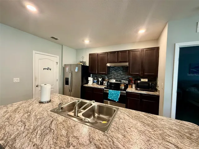 a kitchen with a refrigerator sink and wooden cabinets