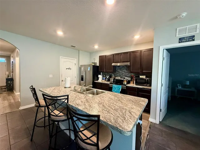 a kitchen with stainless steel appliances kitchen island granite countertop a dining table and chairs