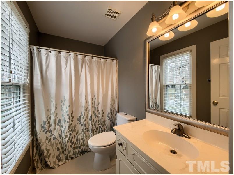 2521 Village Grove Road Raleigh, NC 27613 - Photo 17 of 25 a bathroom with a sink a toilet and a mirror