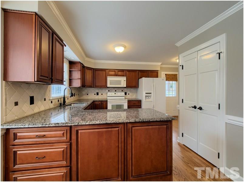 2521 Village Grove Road Raleigh, NC 27613 - Photo 5 of 25 a kitchen with stainless steel appliances granite countertop a sink a stove and a refrigerator