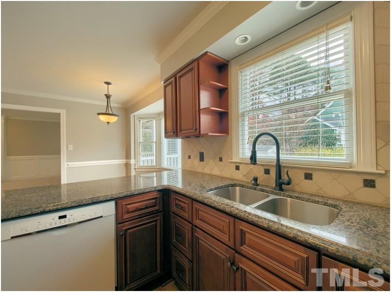 2521 Village Grove Road Raleigh, NC 27613 - Photo 8 of 25 a kitchen with stainless steel appliances granite countertop a sink a stove and a wooden cabinets