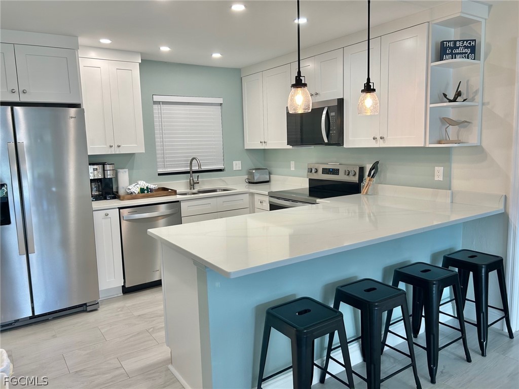 5117 Sea Bell Road, Unit E104 Sanibel, FL 33957 - Photo 1 of 31 a kitchen with white cabinets stainless steel appliances and kitchen island