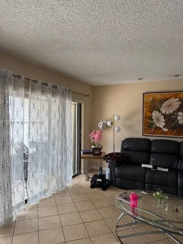 a living room with furniture a flat screen tv and a floor to ceiling window