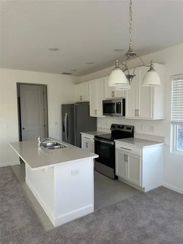 a kitchen with kitchen island granite countertop stainless steel appliances a stove a sink a microwave and a refrigerator