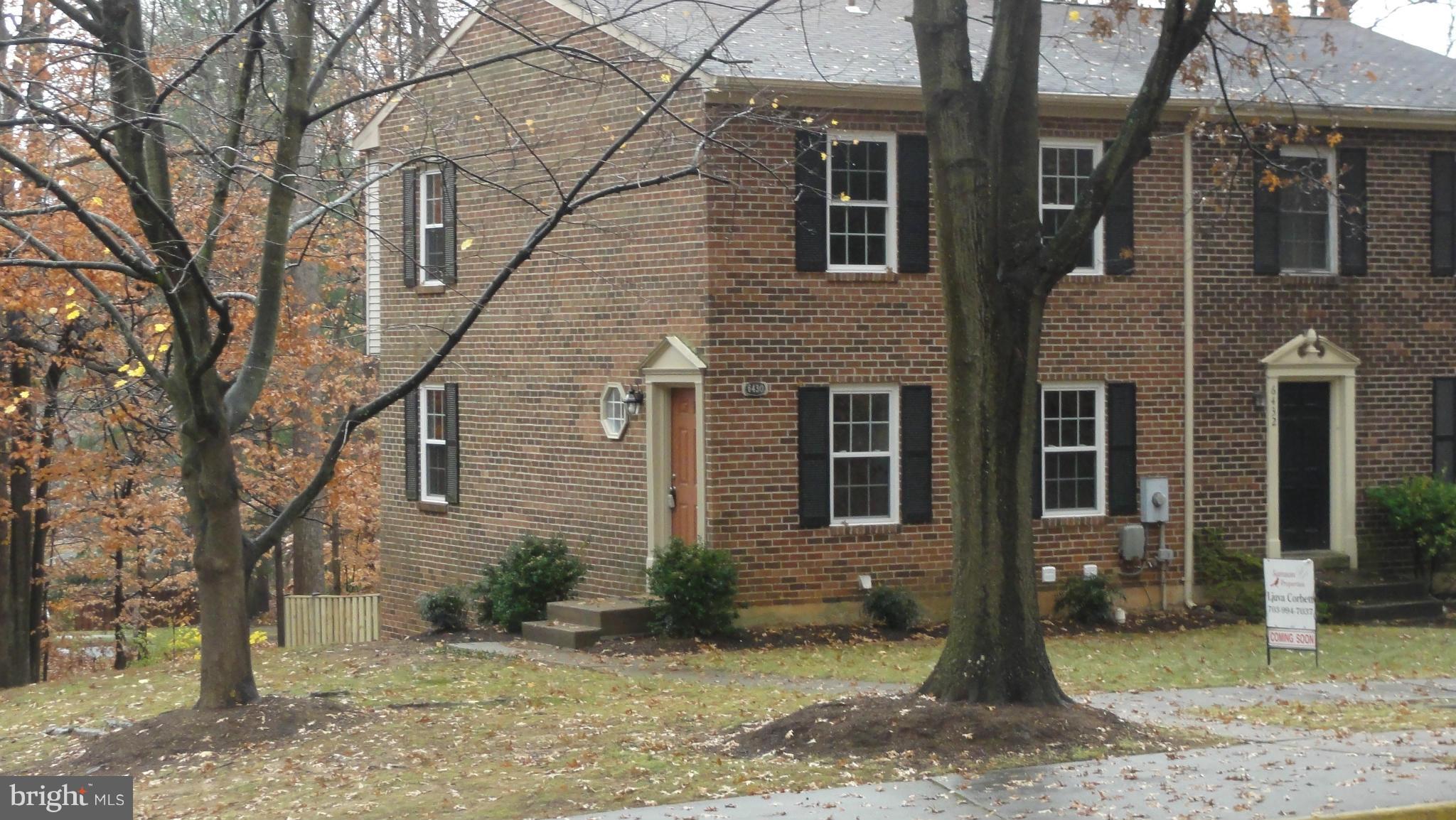 a view of a brick house with large windows and large tree