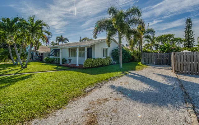 a front view of a house with a garden and trees