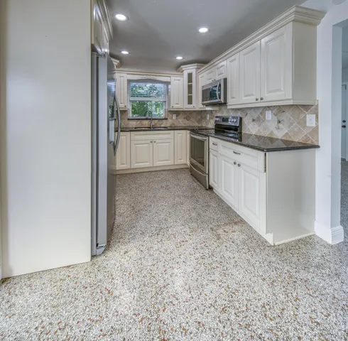 a kitchen with stainless steel appliances granite countertop a stove top oven a sink and a refrigerator