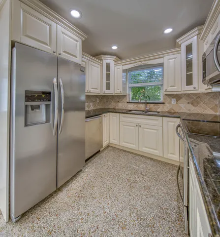 a kitchen with stainless steel appliances granite countertop a refrigerator and a sink