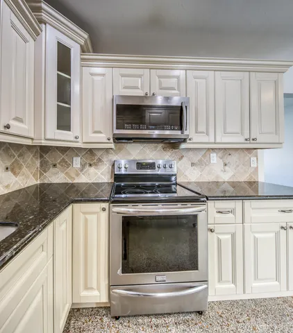 a kitchen with granite countertop a stove top oven microwave and cabinets