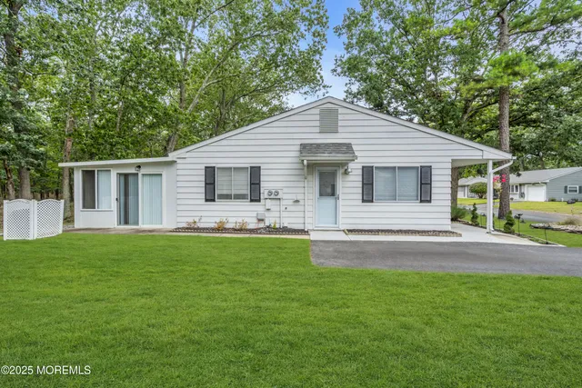 a view of a house with a yard and a large tree