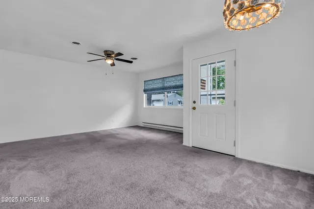 an empty room with windows and ceiling fan