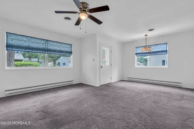an empty room with ceiling fan and windows